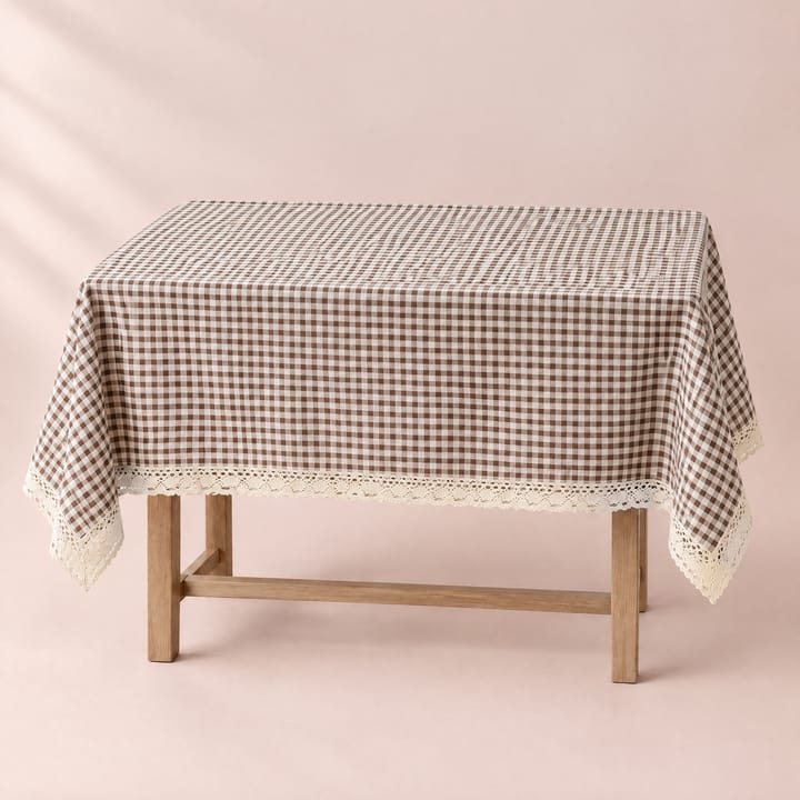 Brown gingham tablecloth with a cream lace edge on a wooden dining table